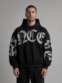 Man draagt heren oversized hoodie met gothic letterprint, vooraanzicht