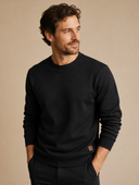 Man draagt een zwarte sweatshirt met ronde hals, driekwartaanzicht