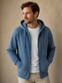 Man draagt een blauwe zip-up hoodie met capuchon, driekwart aanzicht